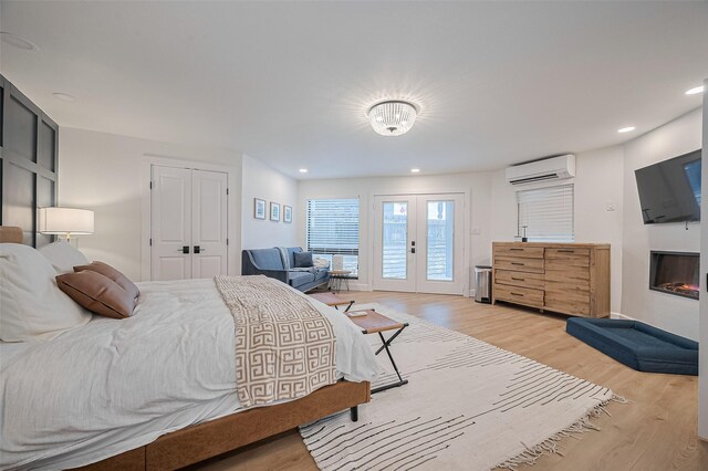 3734 Windswept Dr, Montgomery, TX 77356 - bedroom featuring light wood-style flooring, a wall mounted air conditioner, french doors, a glass covered fireplace, and recessed lighting