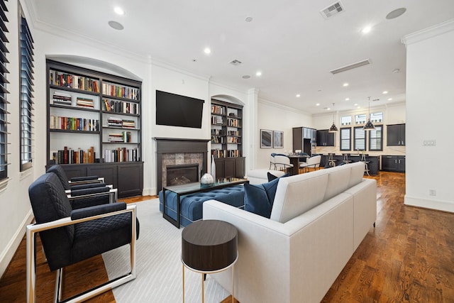 living area featuring visible vents, ornamental molding, a fireplace, recessed lighting, and dark wood-type flooring
