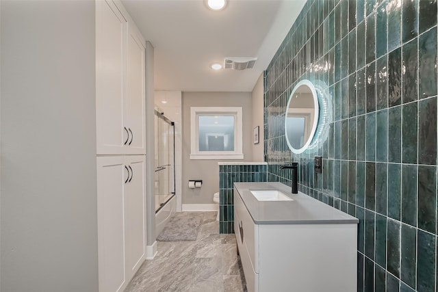 2311 Branard St, Houston, TX 77098 - bathroom with toilet, tile walls, visible vents, combined bath / shower with glass door, and vanity