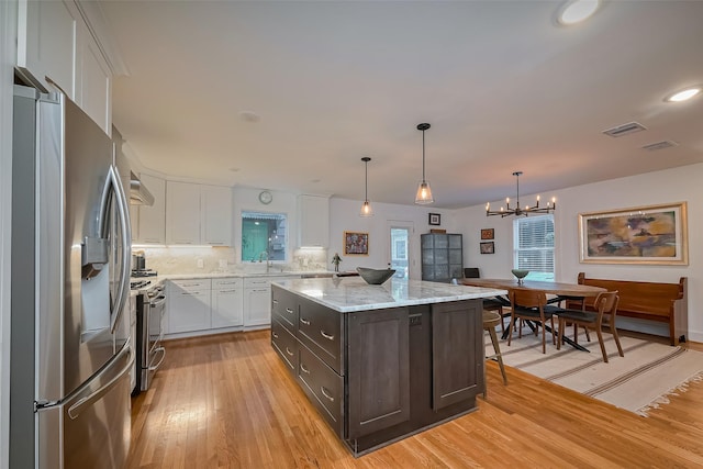 2311 Branard St, Houston, TX 77098 - kitchen with dark brown cabinets, stainless steel appliances, light wood finished floors, white cabinetry, and visible vents