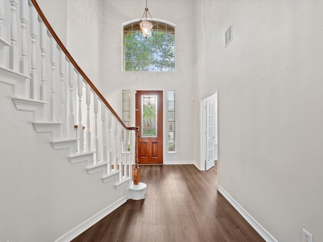 foyer entrance with baseboards, dark wood-style floors, a high ceiling, stairway, and a chandelier