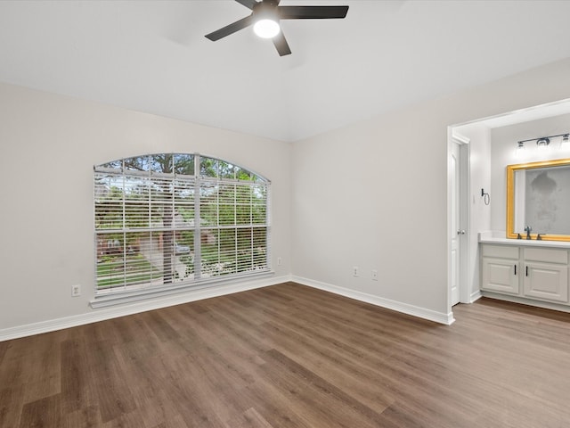 unfurnished room featuring wood finished floors, a ceiling fan, baseboards, and vaulted ceiling