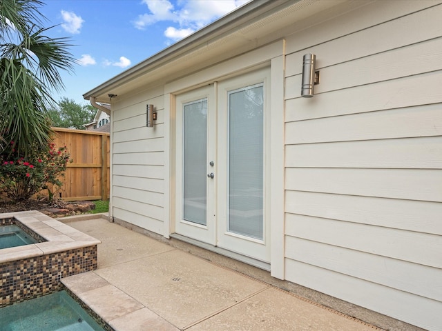 property entrance featuring fence, a patio area, and an outdoor hot tub