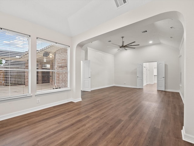 unfurnished living room featuring vaulted ceiling, arched walkways, a ceiling fan, wood finished floors, and baseboards