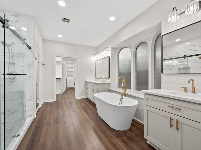 full bathroom featuring a shower stall, wood finished floors, recessed lighting, and a walk in closet