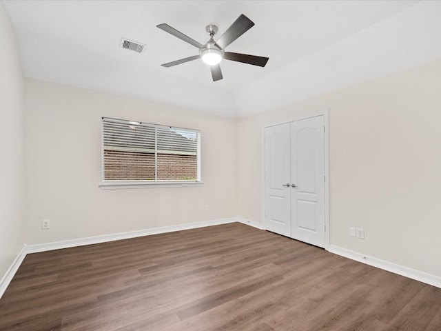 unfurnished bedroom with wood finished floors, a closet, baseboards, and a ceiling fan
