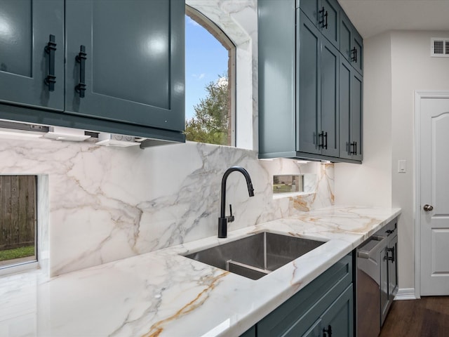 kitchen featuring a sink, decorative backsplash, light stone counters, stainless steel dishwasher, and dark wood finished floors