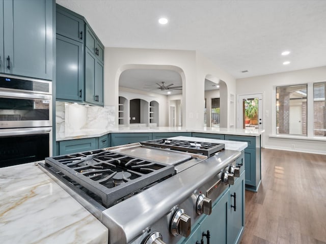 kitchen with stainless steel appliances, arched walkways, ceiling fan, recessed lighting, and decorative backsplash
