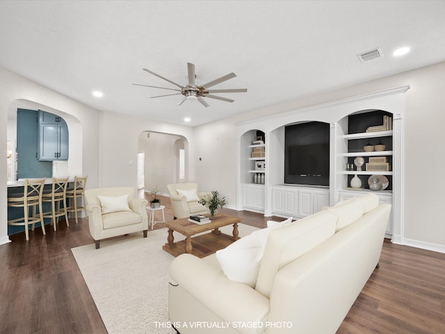 living room featuring arched walkways, ceiling fan, baseboards, dark wood-style flooring, and recessed lighting