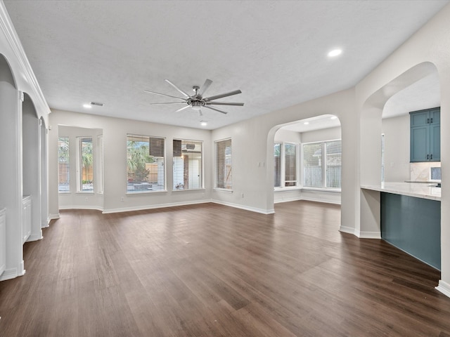 unfurnished living room with a ceiling fan, healthy amount of natural light, dark wood finished floors, and recessed lighting