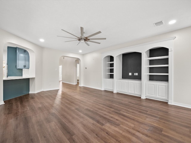 unfurnished living room featuring ceiling fan, dark wood-type flooring, baseboards, recessed lighting, and arched walkways