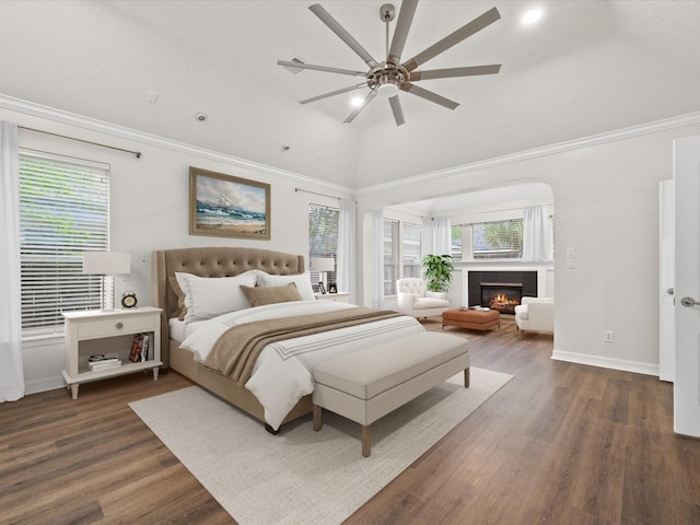 bedroom featuring wood finished floors, a fireplace, crown molding, and baseboards
