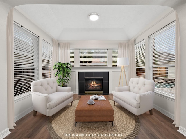 living area featuring wood finished floors, healthy amount of natural light, a tiled fireplace, and lofted ceiling