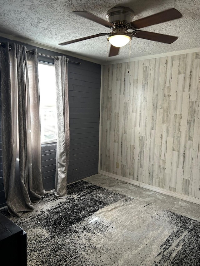 spare room featuring a textured ceiling, a ceiling fan, and wooden walls