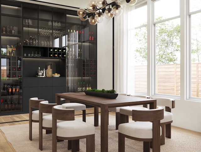 dining room with a bar, wood finished floors, and an inviting chandelier