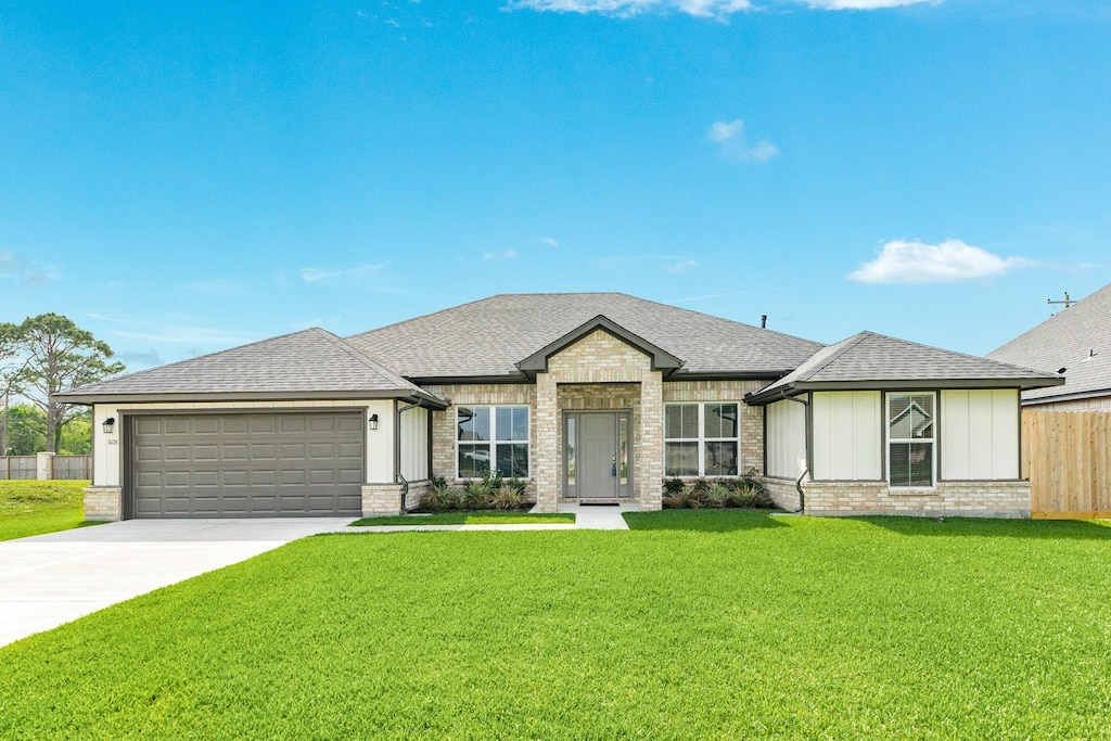 608 Greystone Ln, Angleton, TX 77515 - view of front of home featuring concrete driveway, brick siding, a front lawn, a shingled roof, and a garage