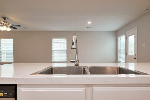 kitchen with visible vents, a ceiling fan, white cabinetry, a sink, and dishwashing machine
