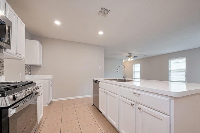 kitchen with a sink, a ceiling fan, stainless steel appliances, visible vents, and decorative backsplash