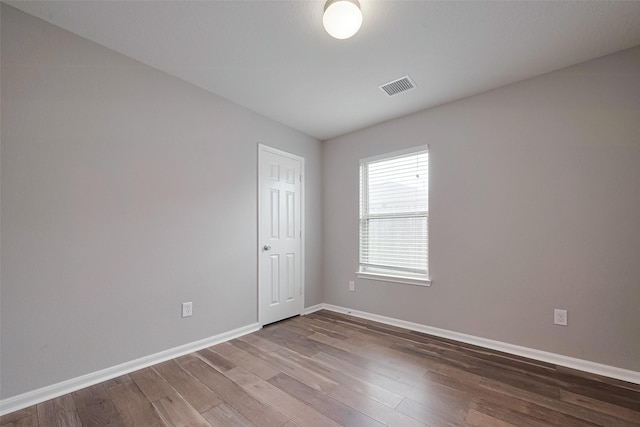 spare room with baseboards, visible vents, and wood finished floors