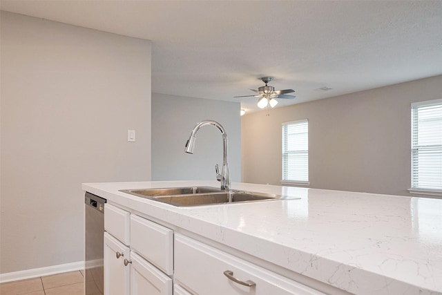 kitchen with light tile patterned floors, a sink, plenty of natural light, and stainless steel dishwasher