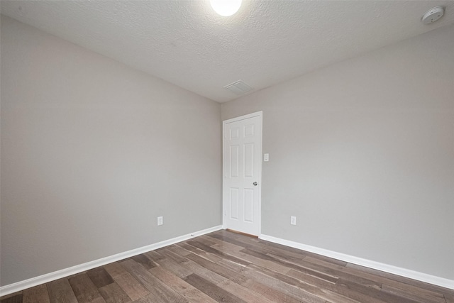 spare room featuring dark wood-style floors, baseboards, and a textured ceiling