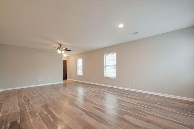 spare room with baseboards, visible vents, light wood-style floors, and ceiling fan
