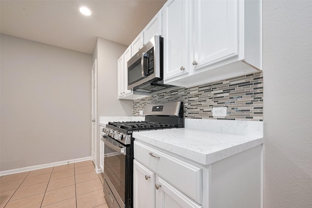 kitchen featuring white cabinetry, light tile patterned floors, baseboards, decorative backsplash, and appliances with stainless steel finishes