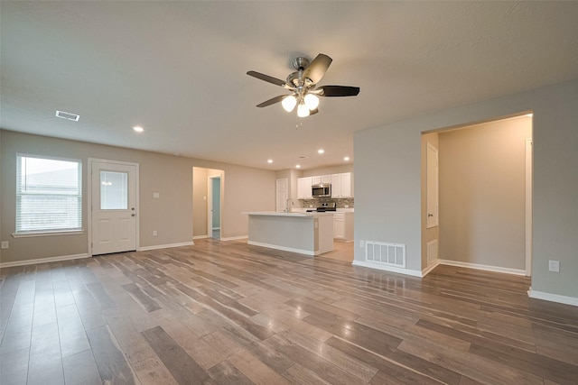 unfurnished living room featuring visible vents, a ceiling fan, and wood finished floors