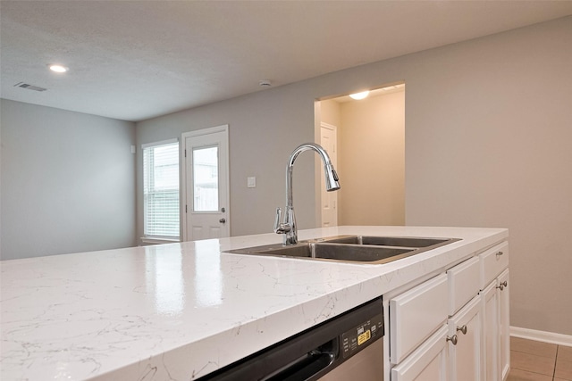 kitchen with stainless steel dishwasher, a sink, visible vents, white cabinets, and light stone countertops
