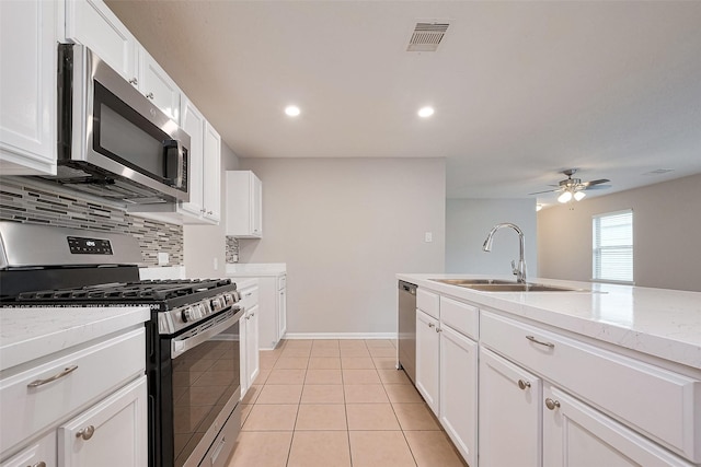 kitchen featuring a sink, tasteful backsplash, light tile patterned floors, stainless steel appliances, and white cabinets