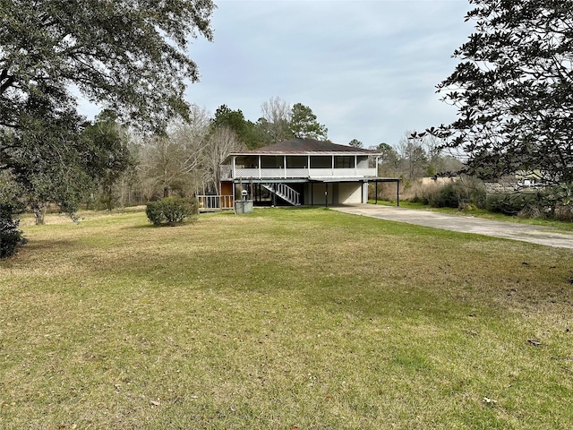 exterior space with concrete driveway, a yard, and stairs
