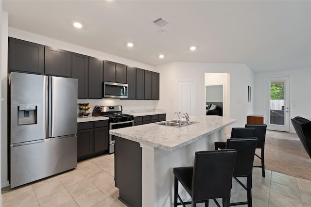 kitchen featuring a sink, a breakfast bar area, light tile patterned floors, stainless steel appliances, and light countertops