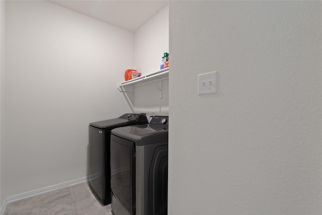 clothes washing area with separate washer and dryer, baseboards, and laundry area