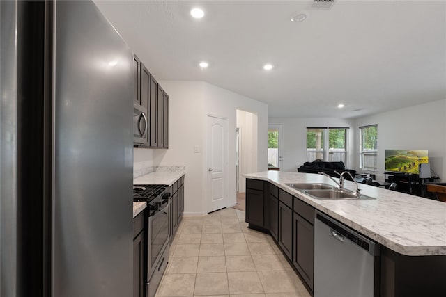 kitchen with a sink, open floor plan, a kitchen island with sink, stainless steel appliances, and light countertops