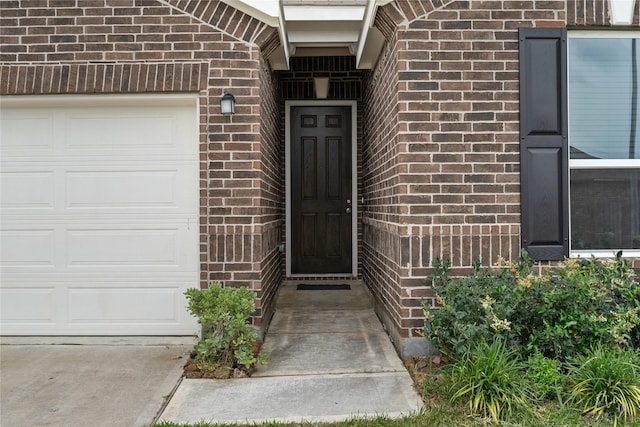 property entrance featuring a garage and brick siding