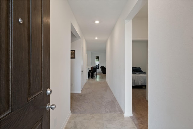 hall featuring light carpet, baseboards, and recessed lighting