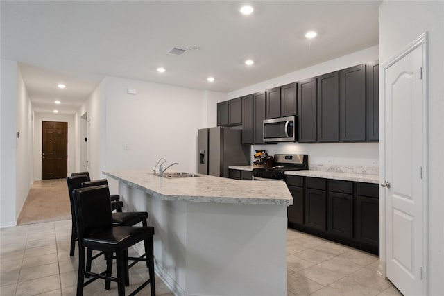 kitchen featuring stainless steel appliances, a kitchen island with sink, a sink, and recessed lighting