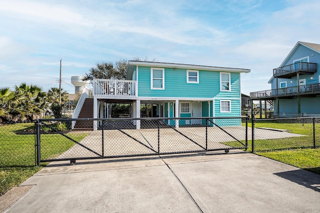 16519 Mansvelt Rd, Jamaica Beach, TX 77554 - raised beach house with stairway, a fenced front yard, a front lawn, driveway, and a carport
