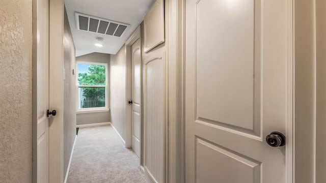 corridor featuring light colored carpet, visible vents, and baseboards