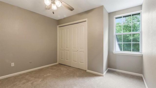 unfurnished bedroom with baseboards, a closet, and light carpet