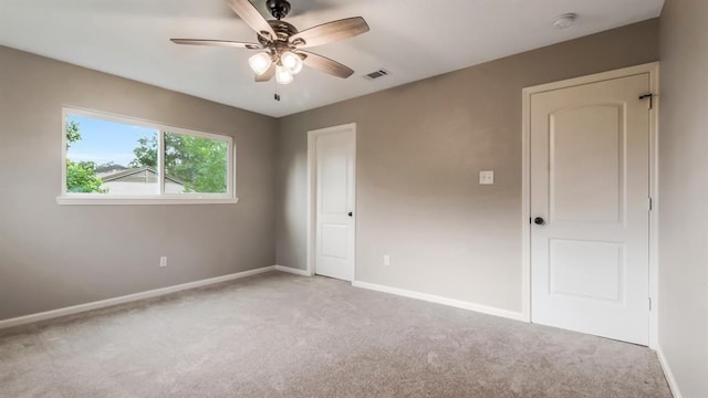 interior space featuring baseboards, ceiling fan, visible vents, and light carpet