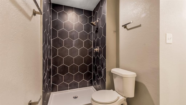 full bathroom featuring toilet, a textured wall, and a shower stall
