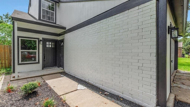 entrance to property with brick siding and fence