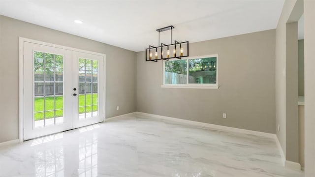 unfurnished dining area featuring baseboards, marble finish floor, french doors, and a chandelier