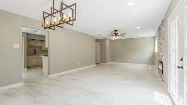 unfurnished living room featuring baseboards, marble finish floor, recessed lighting, a sink, and ceiling fan with notable chandelier
