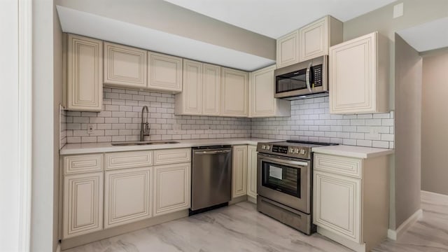 kitchen featuring light countertops, cream cabinetry, a sink, and appliances with stainless steel finishes
