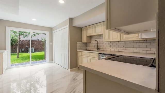 kitchen featuring cream cabinets, light countertops, a sink, and marble finish floor
