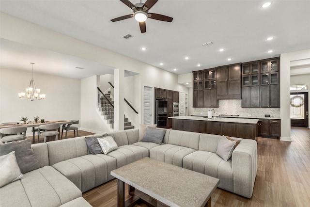 living area with recessed lighting, stairway, visible vents, dark wood-style flooring, and ceiling fan with notable chandelier