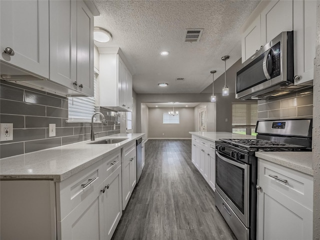 1701 N Park Way Dr, Deer Park, TX 77536 - kitchen with stainless steel appliances, a sink, white cabinets, dark wood finished floors, and backsplash