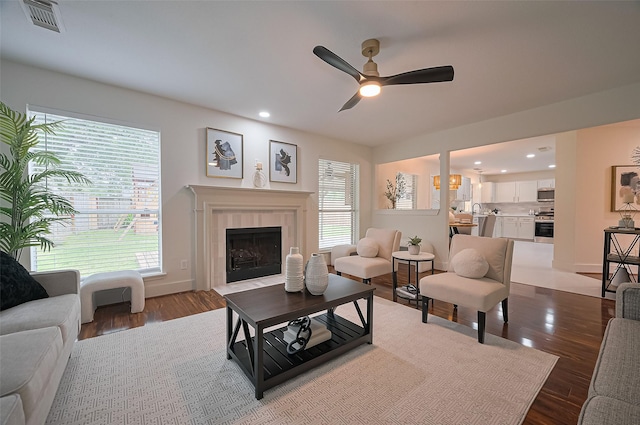 5615 Haven Point Dr, Houston, TX 77084 - living area featuring a tile fireplace, visible vents, a ceiling fan, and dark wood-type flooring